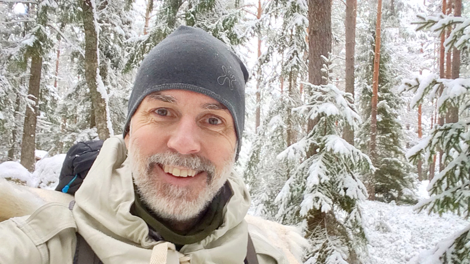 En selfie på en leende man i en snöig granskog. 