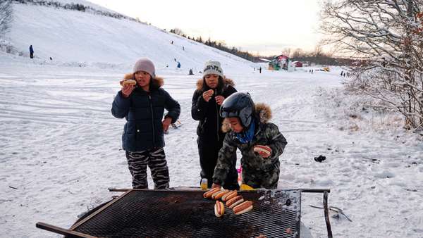 Tre barn grillar korv ute i snön