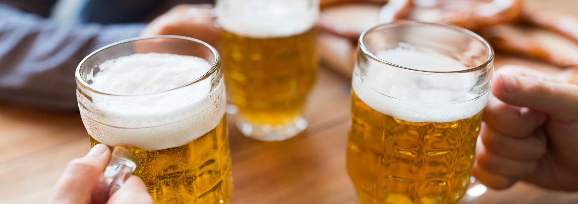 Händer med öl i glas på pub