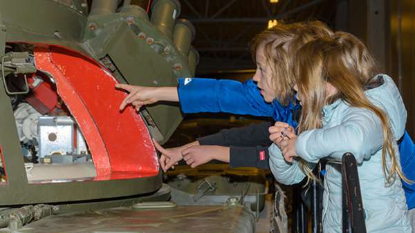 Barn som tittar på en militär tank.