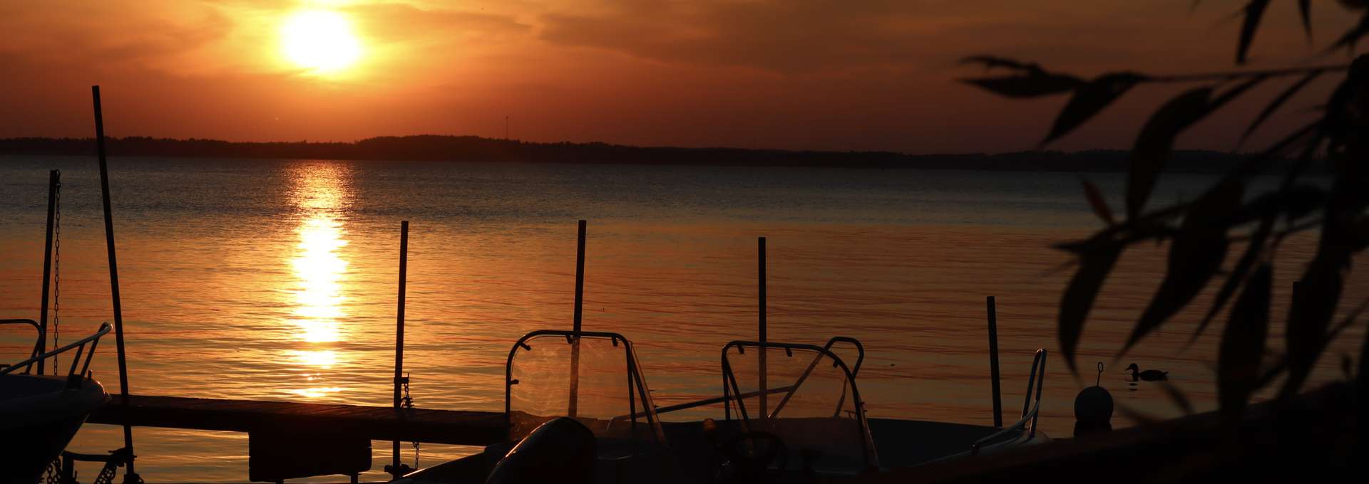 Båtbrygga vid sjö i vacker solnedgång