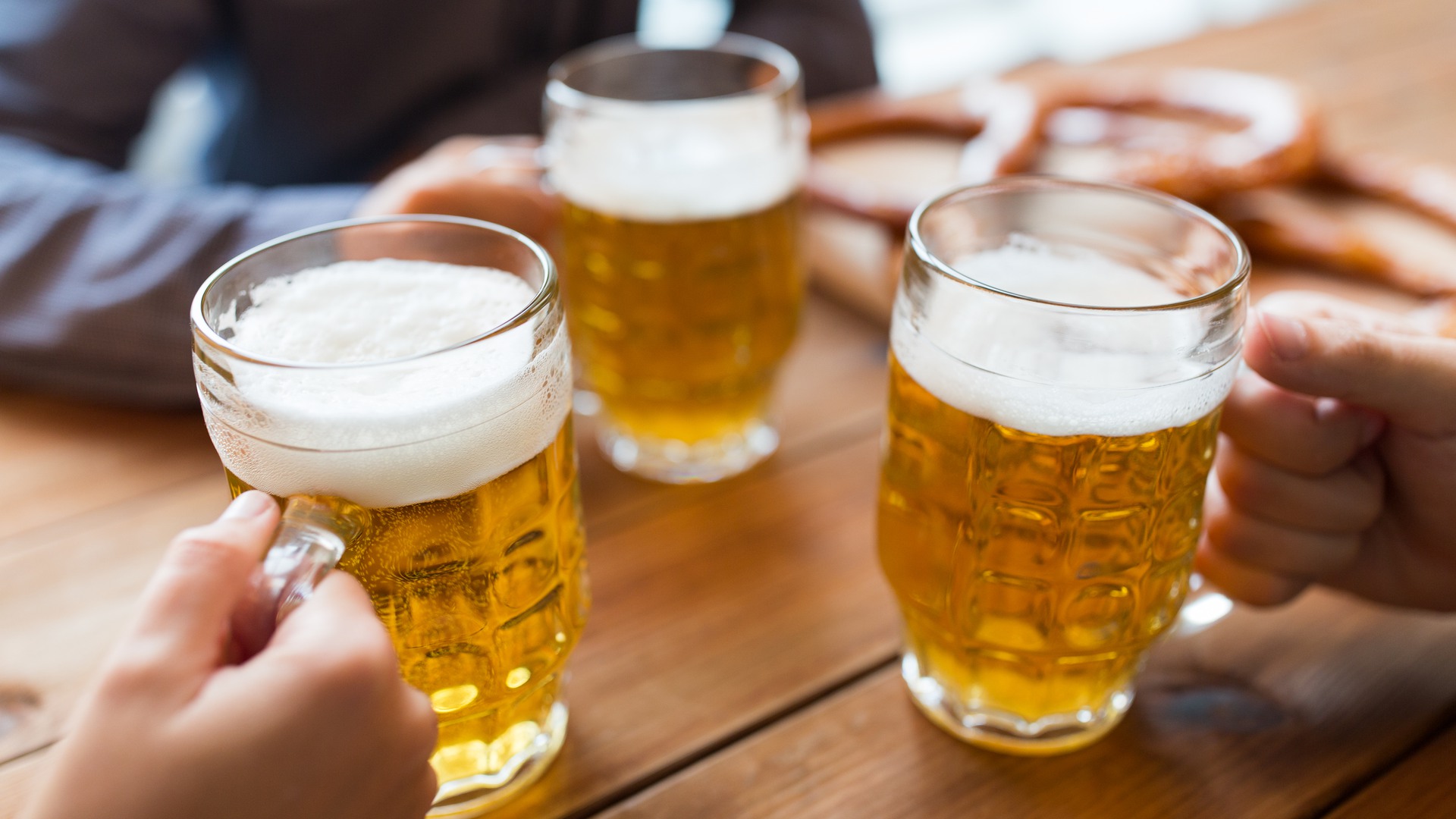 Händer med öl i glas på pub