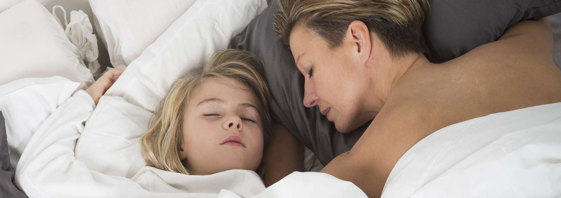 Mamma och dotter sover bredvid varandra i en dubbelsäng